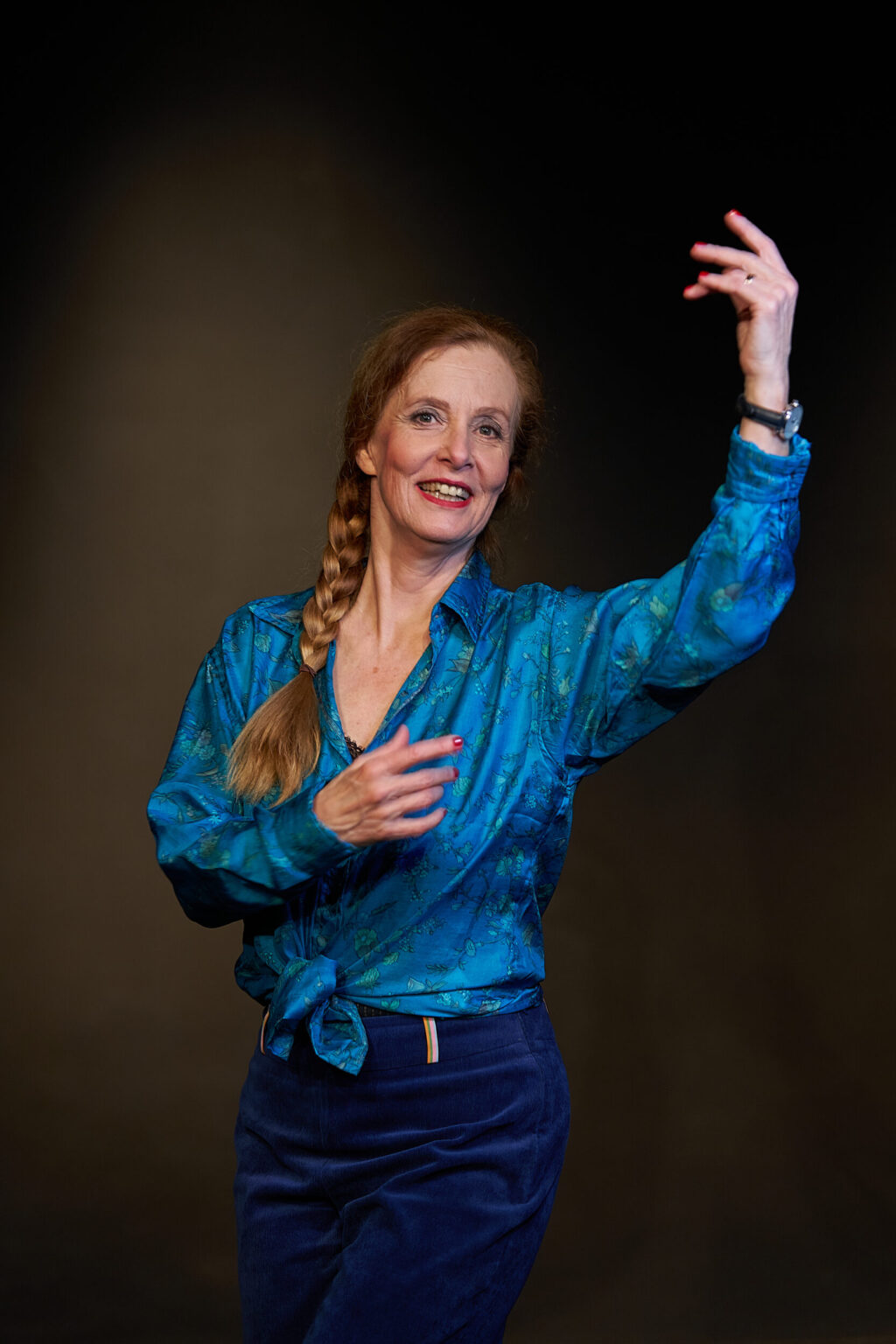 Marie Oser mit blauer Bluse, Zopf und erhobenen Armen